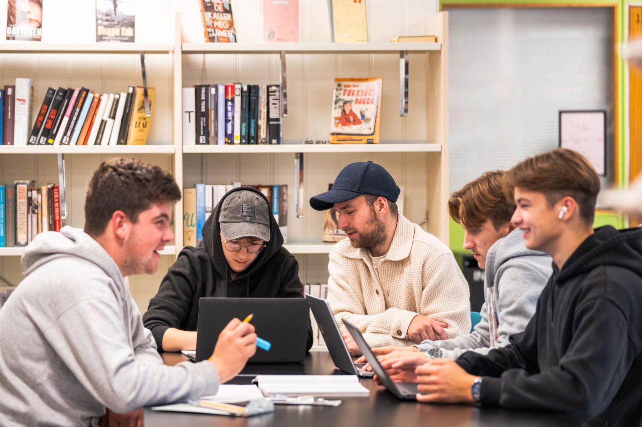 Bilete av miljøkoordinator saman med elevar på biblioteket